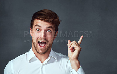 Buy stock photo Studio portrait of a handsome young man pointing excitedly to copyspace against a dark background