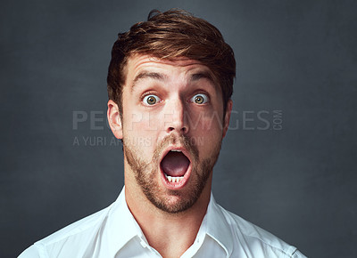 Buy stock photo Studio portrait of a handsome young man looking shocked against a grey background