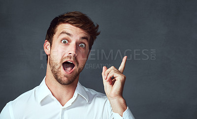 Buy stock photo Studio portrait of a handsome young man pointing excitedly to copyspace against a dark background