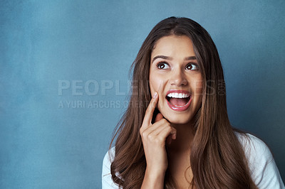 Buy stock photo Studio shot of an attractive young woman looking thoughtful a blue background