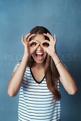 Buy stock photo Woman, binocular hands and eyes in studio portrait for comic, funny face and smile for casual fashion. Gen z model, ok hand gesture and crazy, screaming and positive mindset on gray background