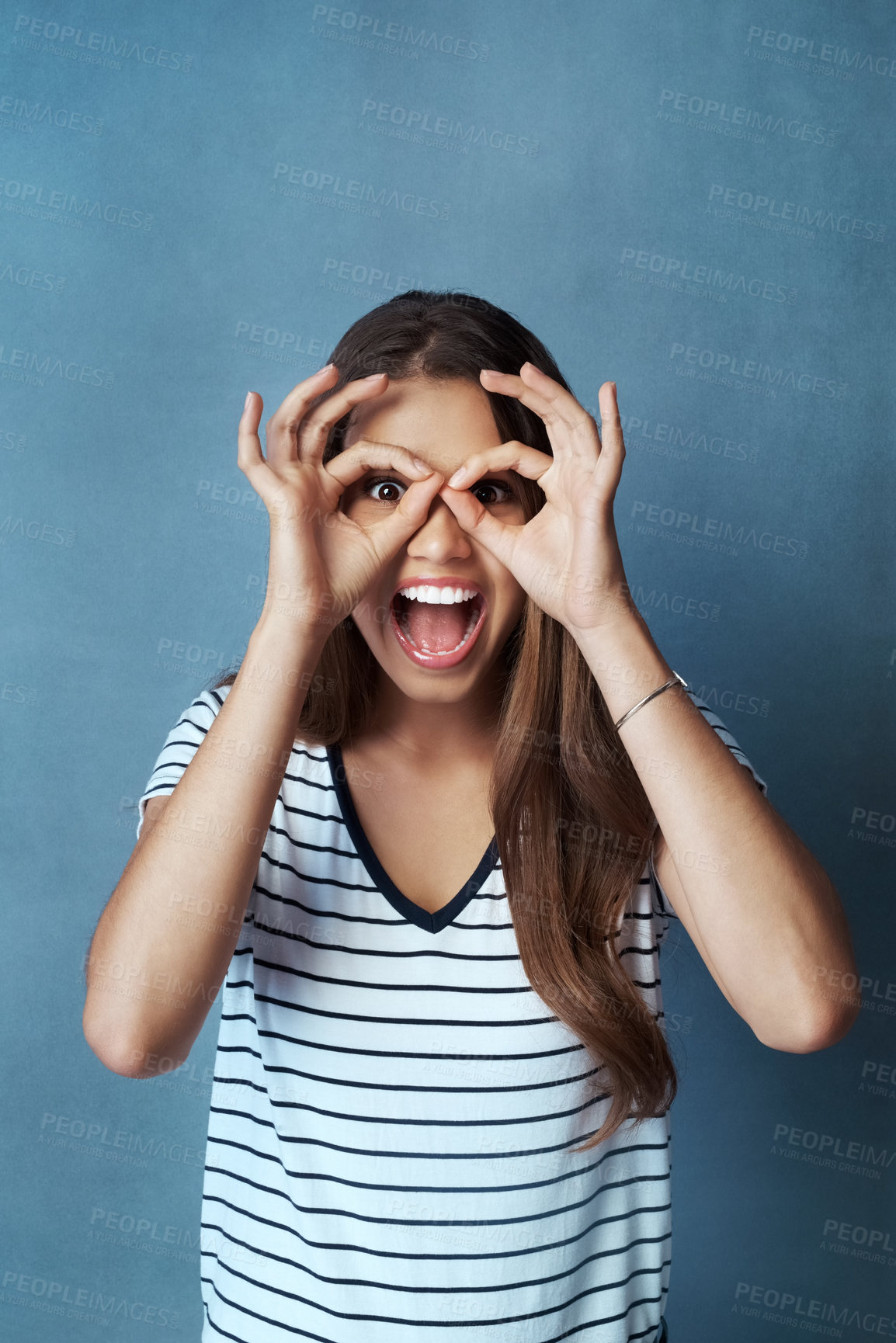 Buy stock photo Woman, binocular hands and eyes in studio portrait for comic, funny face and smile for casual fashion. Gen z model, ok hand gesture and crazy, screaming and positive mindset on gray background