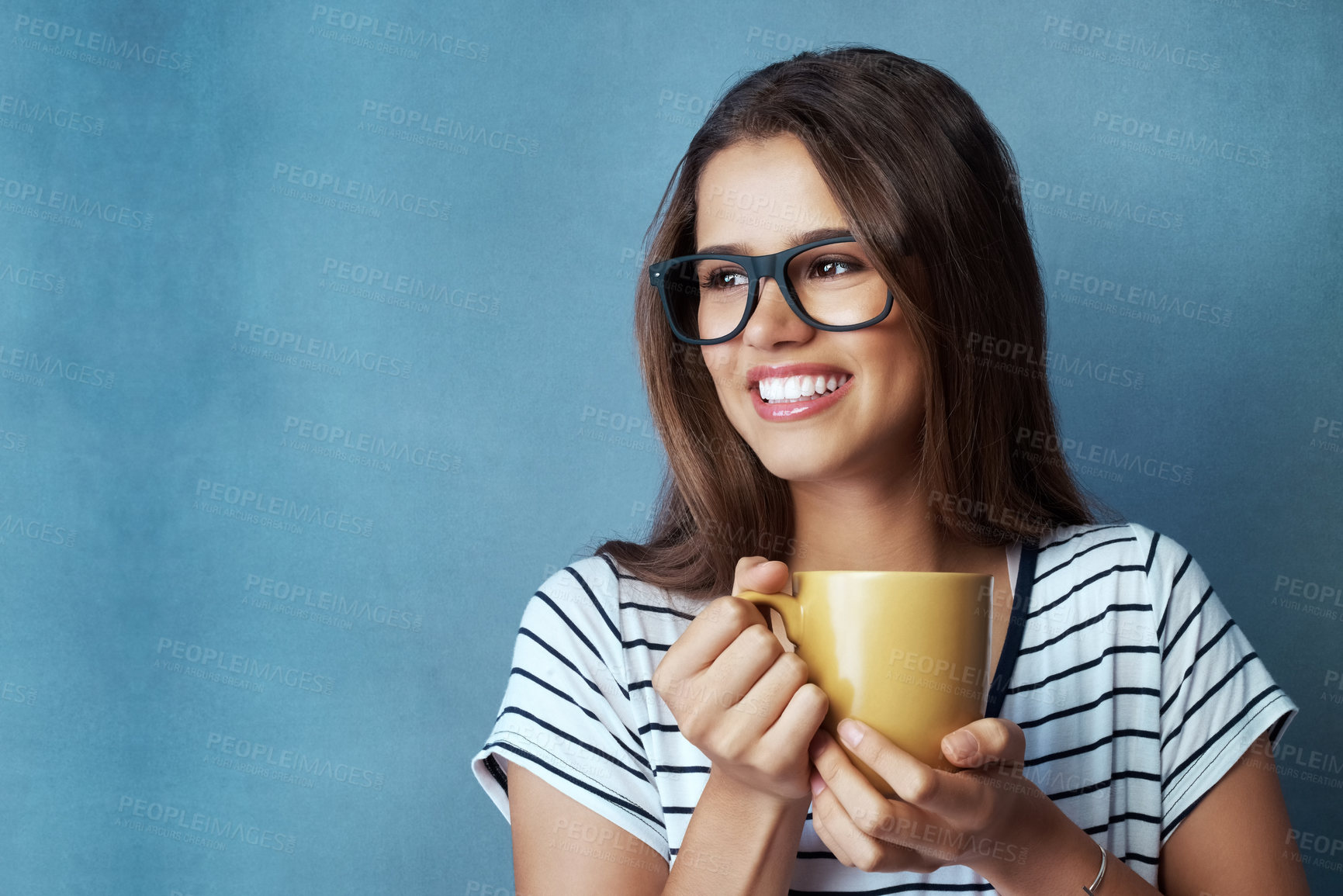 Buy stock photo Woman, student and coffee in studio with thinking, drink and glasses on blue background. Smile, caffeine or energy or mockup for learner person, hands and matcha or green tea for hydration and relax
