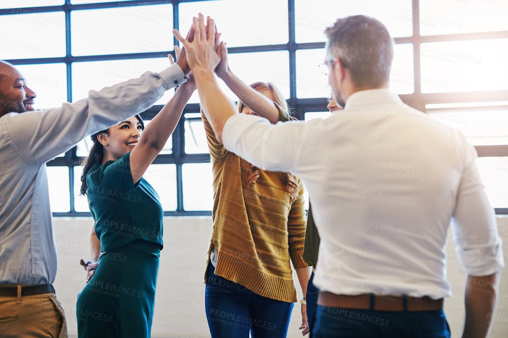 Buy stock photo Cropped shot of a group of colleagues giving each other a high five in a modern office