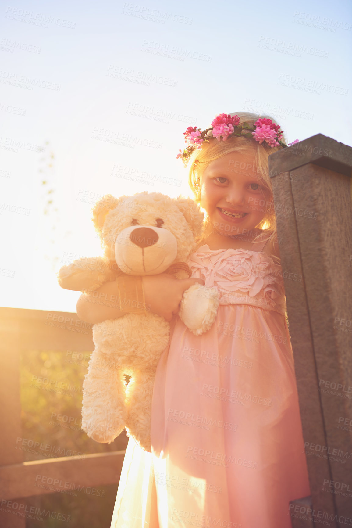 Buy stock photo Shot of a happy little girl holding a teddy bear and looking at the camera while standing on a bridge