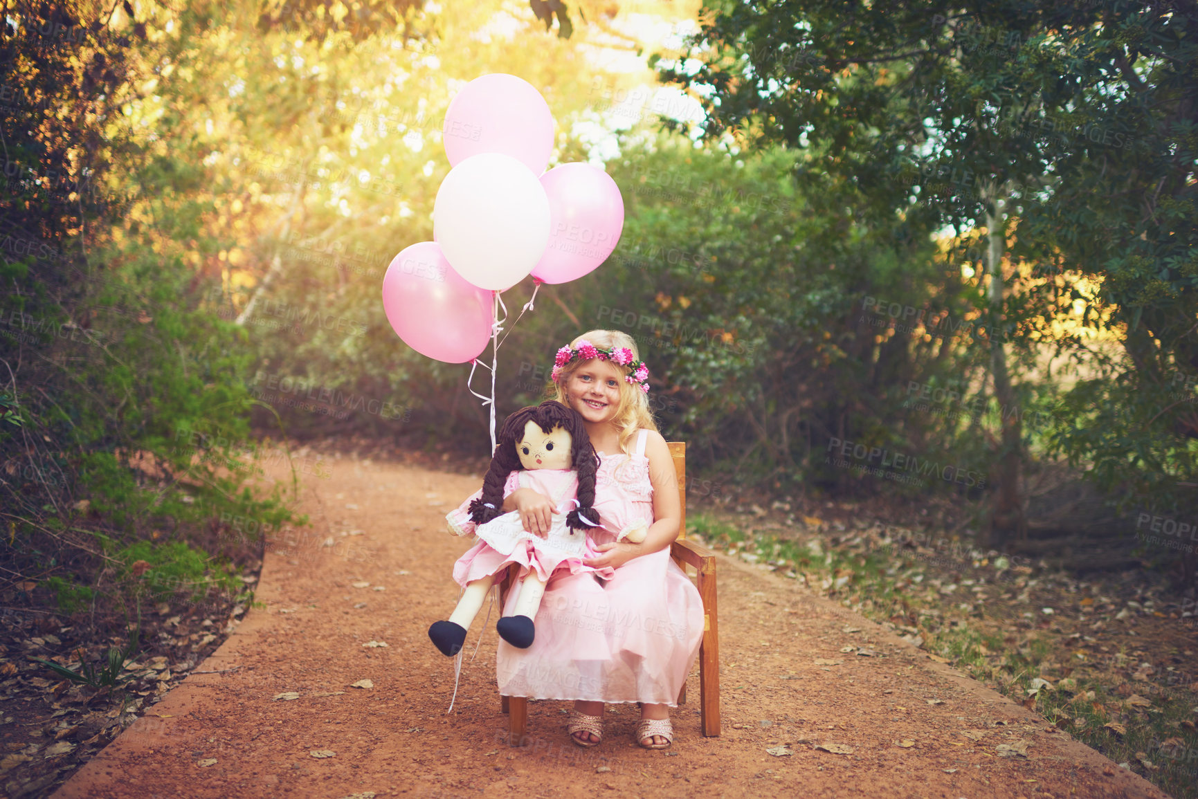 Buy stock photo Portrait, doll and happy child with balloons outdoor for playing game, holiday or fantasy on vacation. Smile, kid and toy at park with flower wreath, dress and cute princess on chair in Switzerland