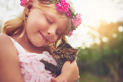 Buy stock photo Shot of a happy little girl holding a kitten and smiling while sitting outside in nature