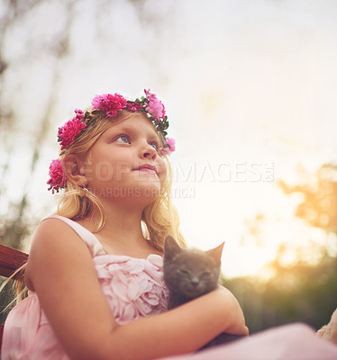 Buy stock photo Shot of a little girl holding a kitten and looking into the distance while standing outside in nature