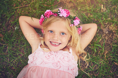 Buy stock photo Shot of a happy little girl looking at the camera while lying on the grass and relaxing outside in nature