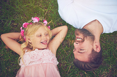 Buy stock photo Shot of a happy daughter and father lying on the ground looking at one another outside in nature