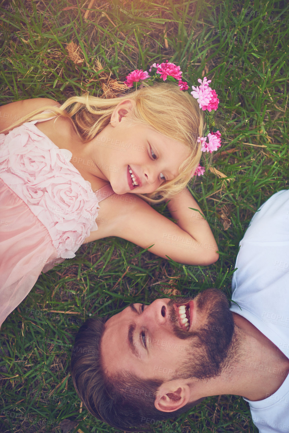 Buy stock photo Shot of a happy daughter and father lying on the ground looking at one another outside in nature