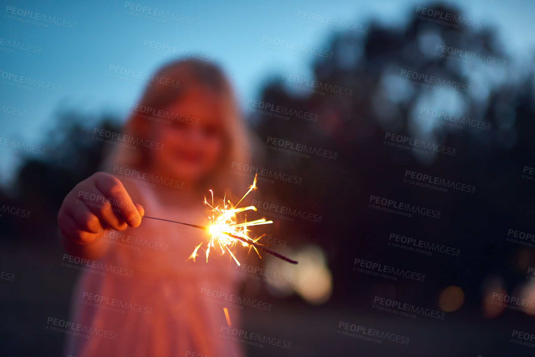 Buy stock photo Shot of an unrecognizable little girl playing with a sparkler at night time outside in nature
