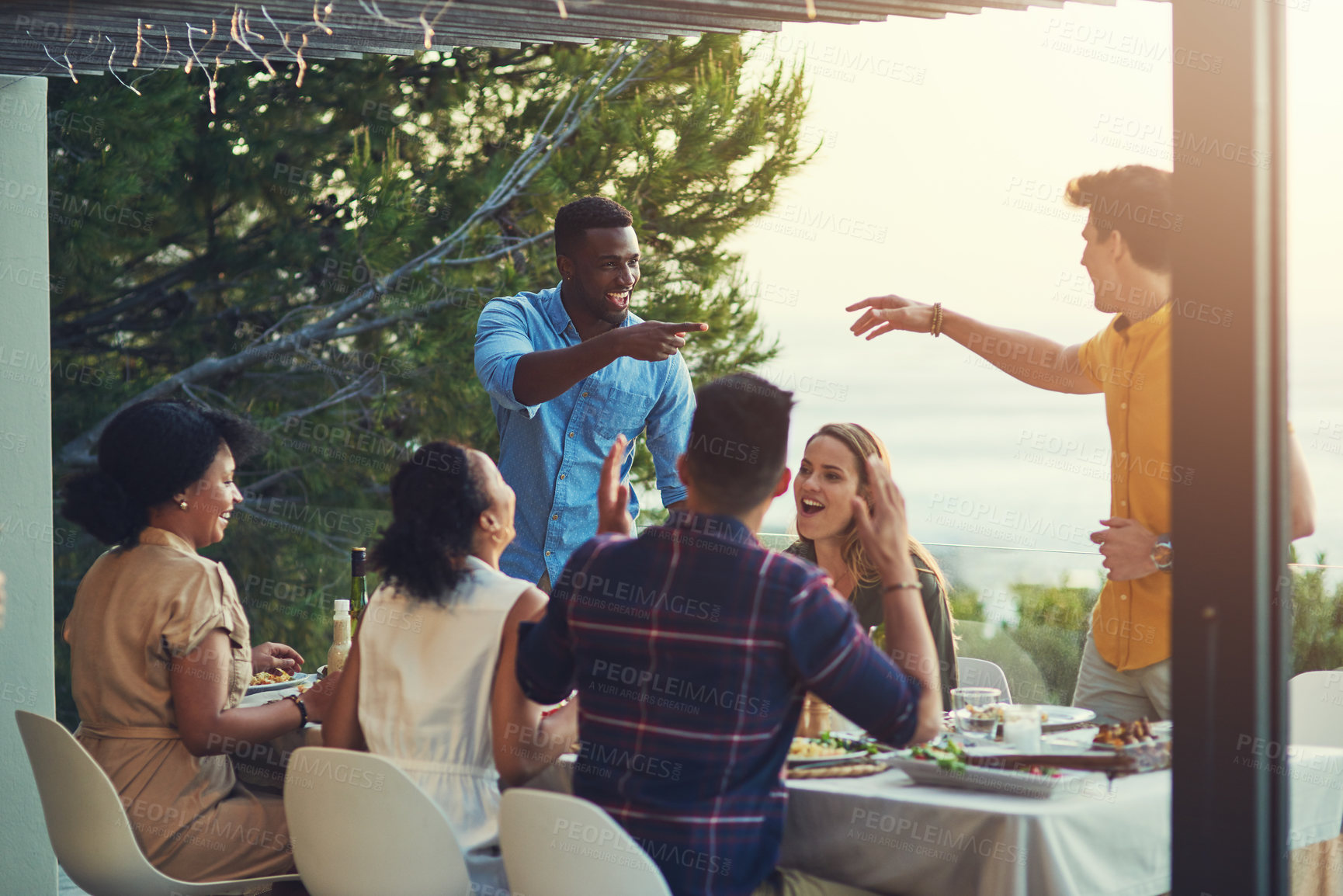 Buy stock photo Shot of a group of friends enjoying a meal and drinks together around a table at a gathering outdoors
