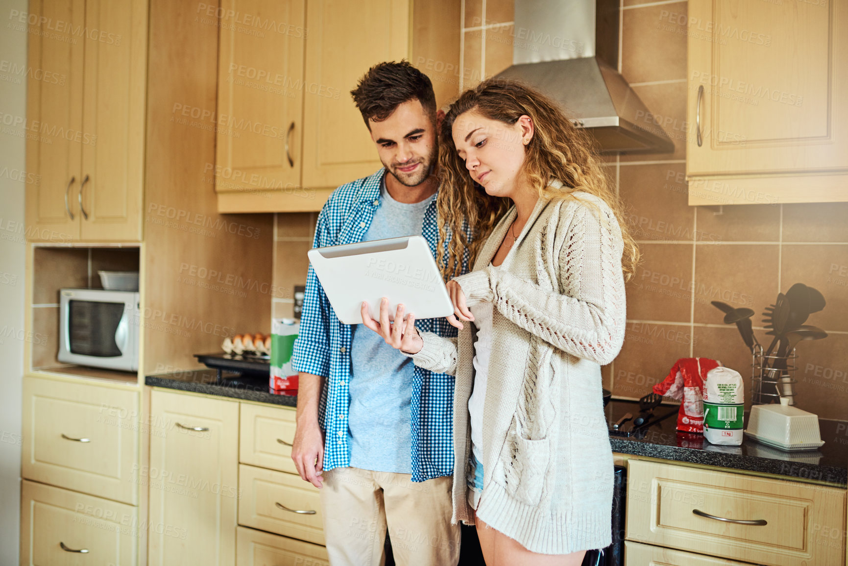 Buy stock photo Cropped shot of a loving couple using a digital tablet together at home