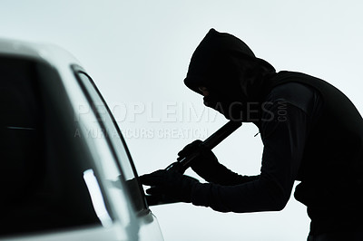 Buy stock photo Shot of a masked criminal using a torch light to look inside an empty car inside a parking lot