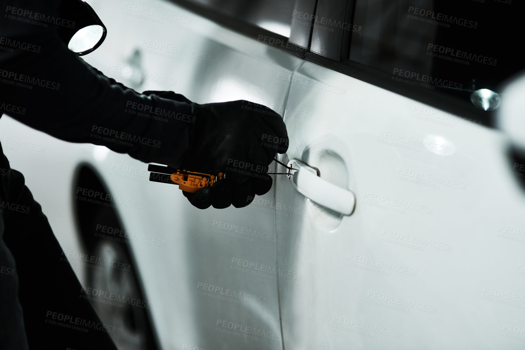 Buy stock photo Shot of an unrecognizable man picking the lock of a car inside a parking lot