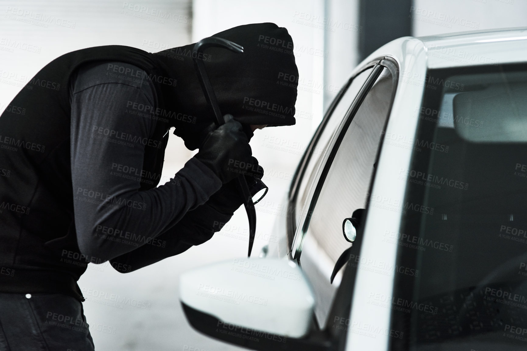 Buy stock photo Shot of a masked criminal using a steel weapon to break inside a car