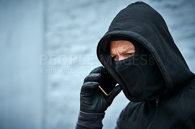 Buy stock photo Shot of a male burglar taking a phone call outdoors