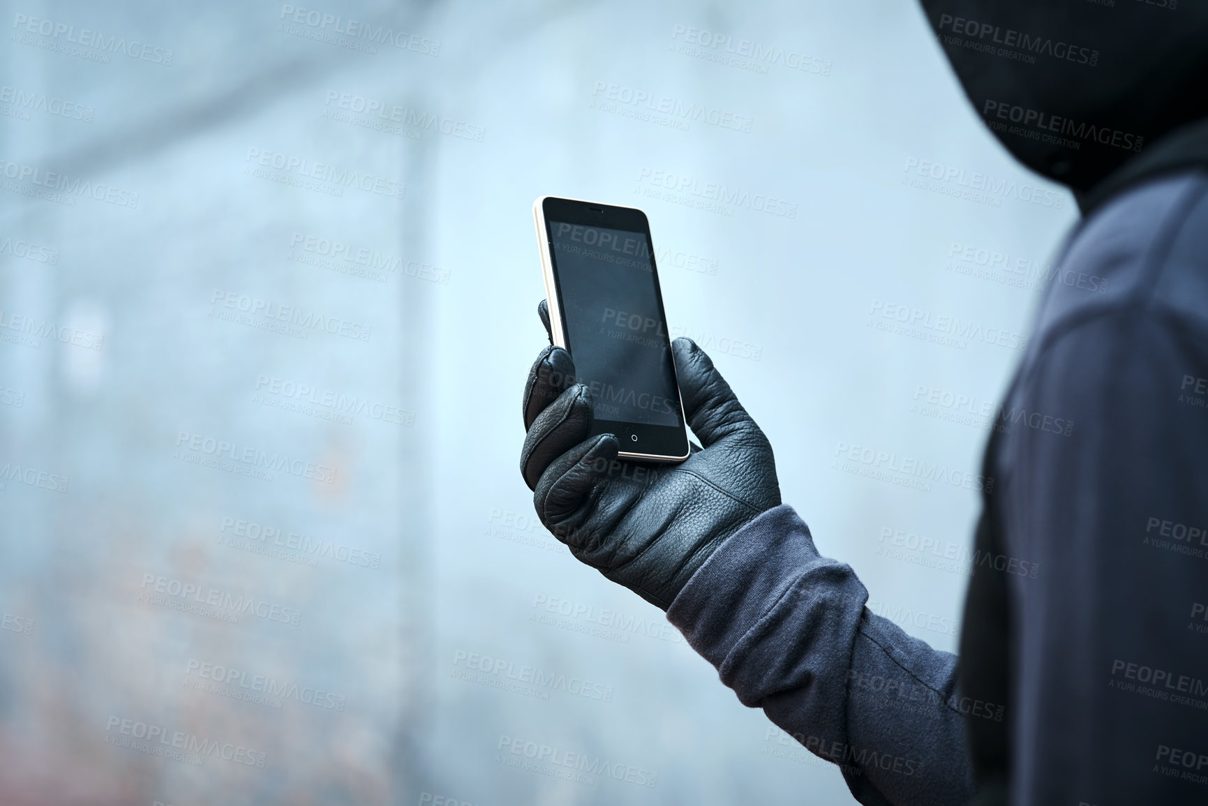 Buy stock photo Shot of a male burglar using his phone outdoors