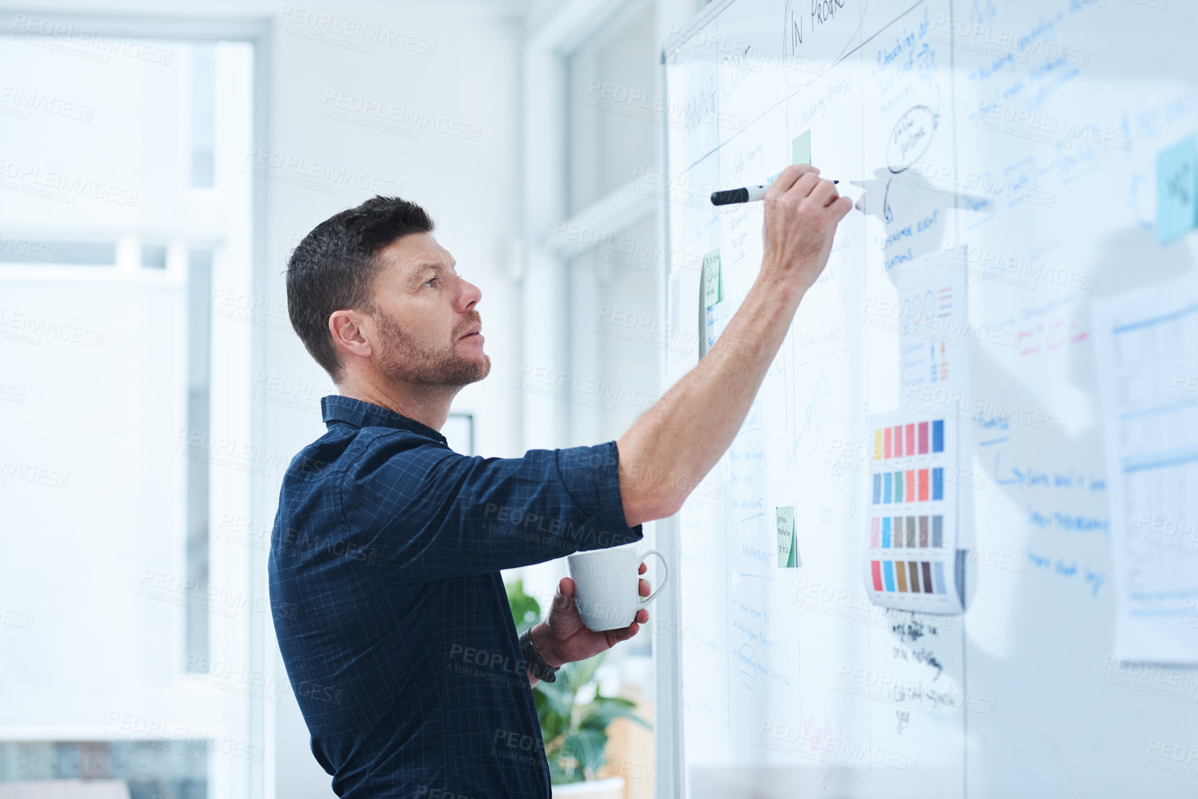 Buy stock photo Shot of a handsome mature male designer working on a whiteboard in the office
