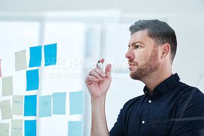 Buy stock photo Shot of a handsome mature businessman working on a glass wipe board in his office