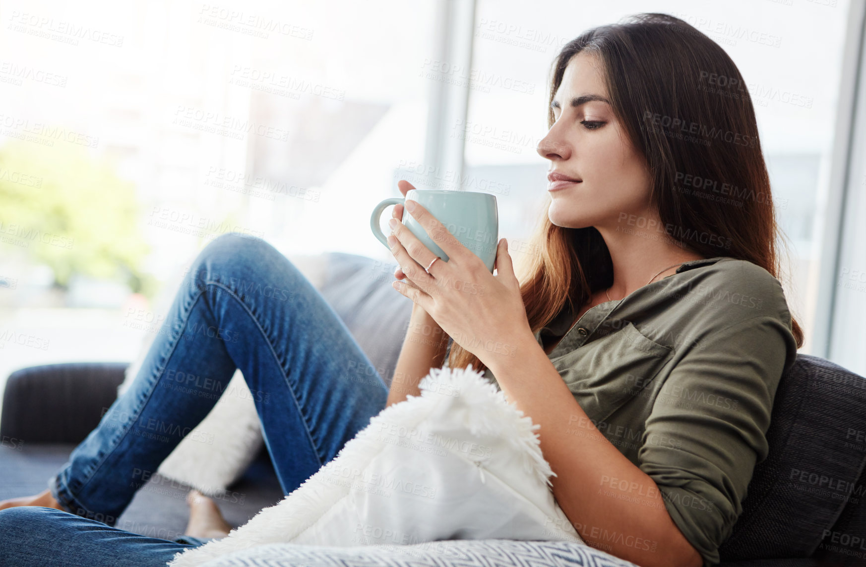 Buy stock photo Shot of a young woman enjoying a cup of coffee while relaxing in the lounge