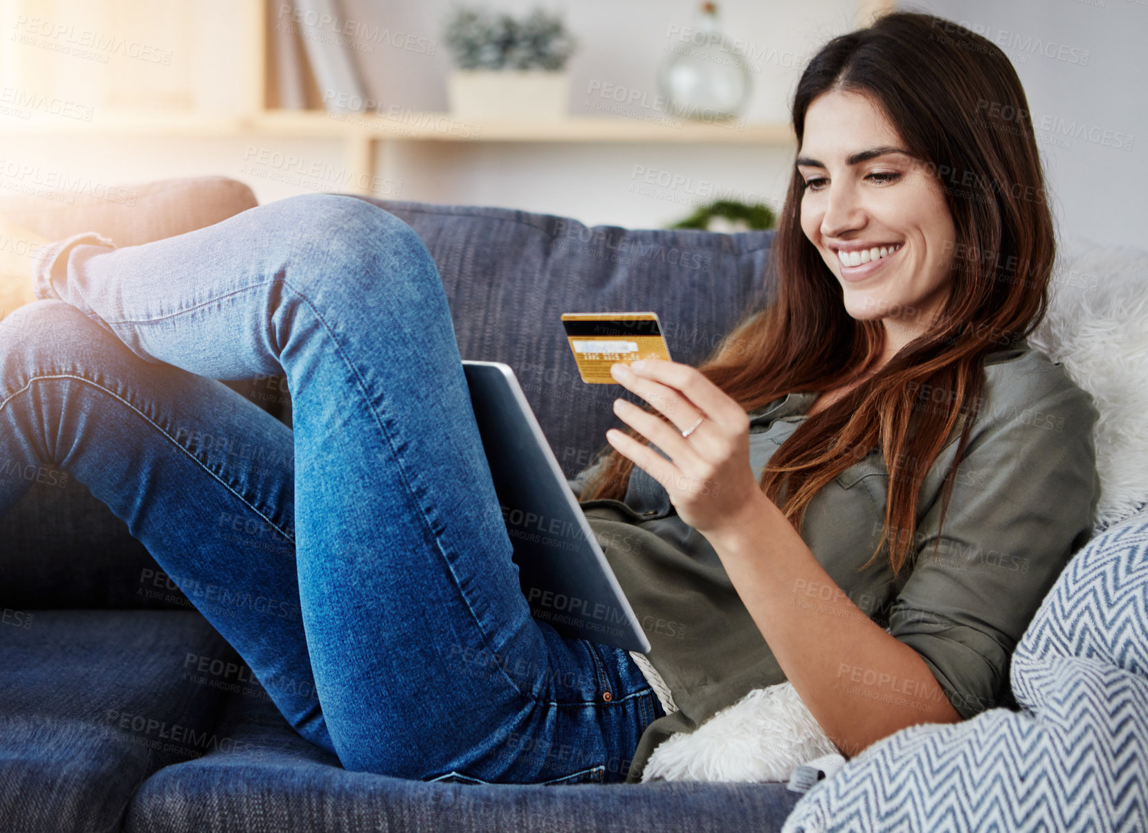 Buy stock photo Shot of a young doing online shopping while relaxing on her couch at home
