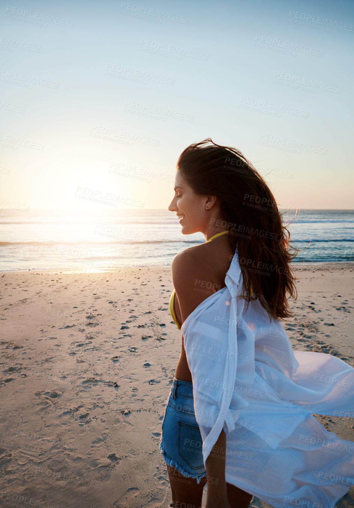 Buy stock photo Shot of a beautiful young woman enjoying herself at the beach at sunset