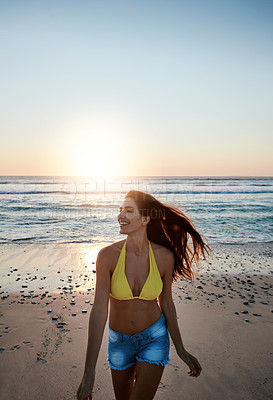 Buy stock photo Shot of a beautiful young woman enjoying herself at the beach at sunset