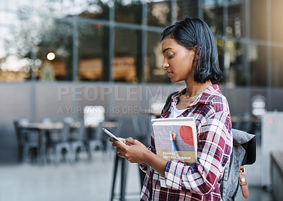 Buy stock photo Cropped shot of an attractive young female student using her cellphone while walking around campus