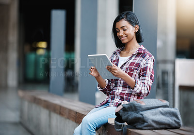 Buy stock photo Cropped shot of an attractive young female student using her tablet while sitting outside on campus