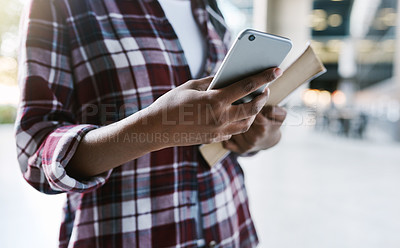 Buy stock photo Cropped shot of an unrecognizable female student using her cellphone while walking around campus