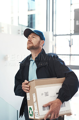 Buy stock photo Shot of a handsome delivery man heading up a flight of stairs with a customer's order