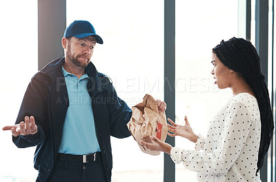 Buy stock photo Shot of a handsome delivery man negotiating with a dissatisfied female customer in the lobby