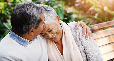 Buy stock photo Shot of an affectionate senior couple sitting down on a bench together and relaxing at the park