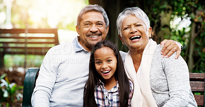 Buy stock photo Portrait of an adorable little girl sitting down on bench with her grandparents at the park