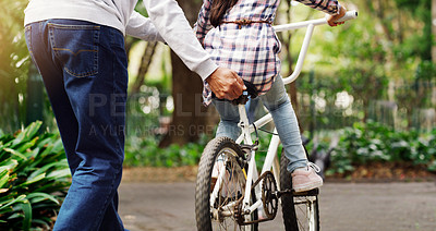 Buy stock photo Father teaching his child to ride a bicycle on a path in an outdoor green community park. Love, bonding and closeup of a man helping his girl kid on a bike in garden for fun, exercise and development
