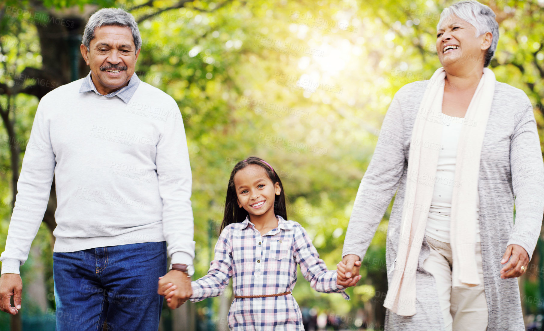 Buy stock photo Park, walk and grandparents holding hands with child, smile and bonding on outdoor adventure together. Old man, woman and girl in nature with love, support and happy family in garden with grandchild.