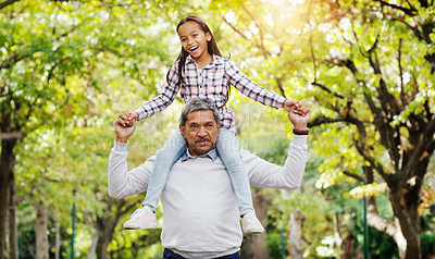 Buy stock photo Shot of a cheerful senior man carrying his granddaughter on his shoulders while spending a day at the park