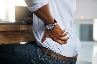 Buy stock photo Shot of an unrecognizable businessman suffering from back pain while trying to work in the office