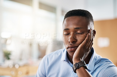 Buy stock photo Shot of an exhausted young businessman taking a quick nap on his hand at work