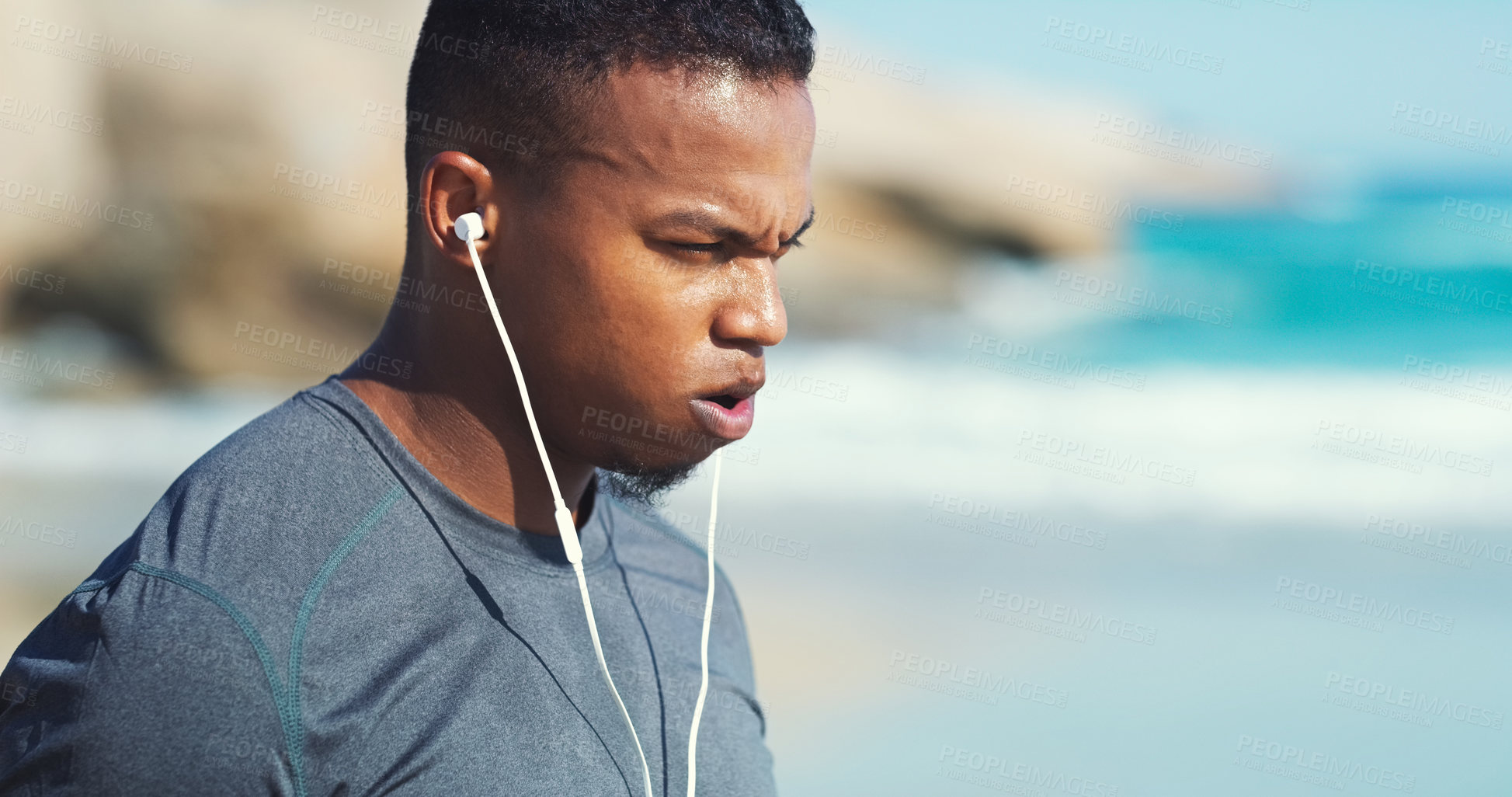 Buy stock photo Fitness, headphones and black man with fatigue at beach to relax on audio, streaming and training. Workout, music and tired runner at ocean, listening to podcast and exercise challenge in nature