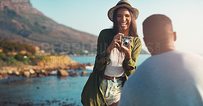 Buy stock photo Happy couple, photography and laughing with camera by beach for funny memory or outdoor moment in nature. Woman or photographer taking picture of man with smile for adventure or tour by ocean coast