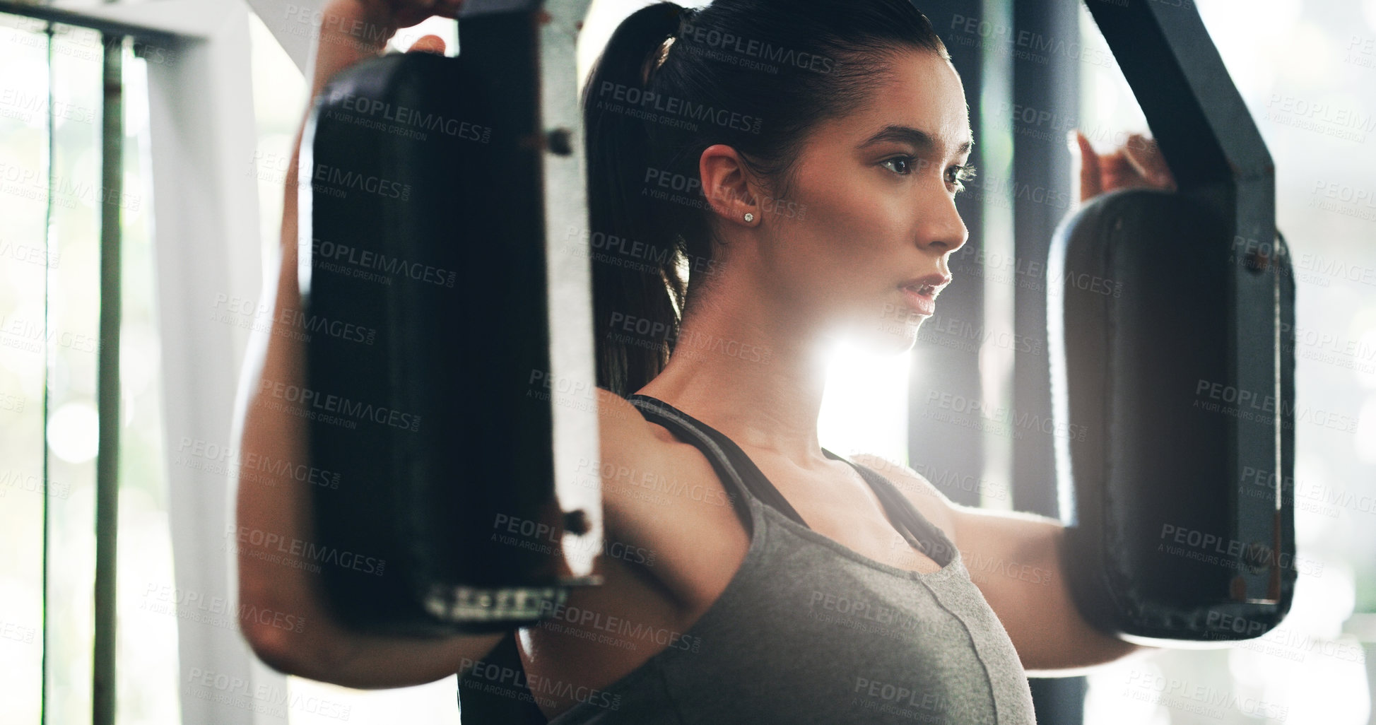 Buy stock photo Cropped shot of an attractive young sportswoman working out with an exercise machine in a gym