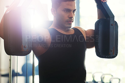 Buy stock photo Cropped shot of a handsome young sportsman working out with an exercise machine in a gym