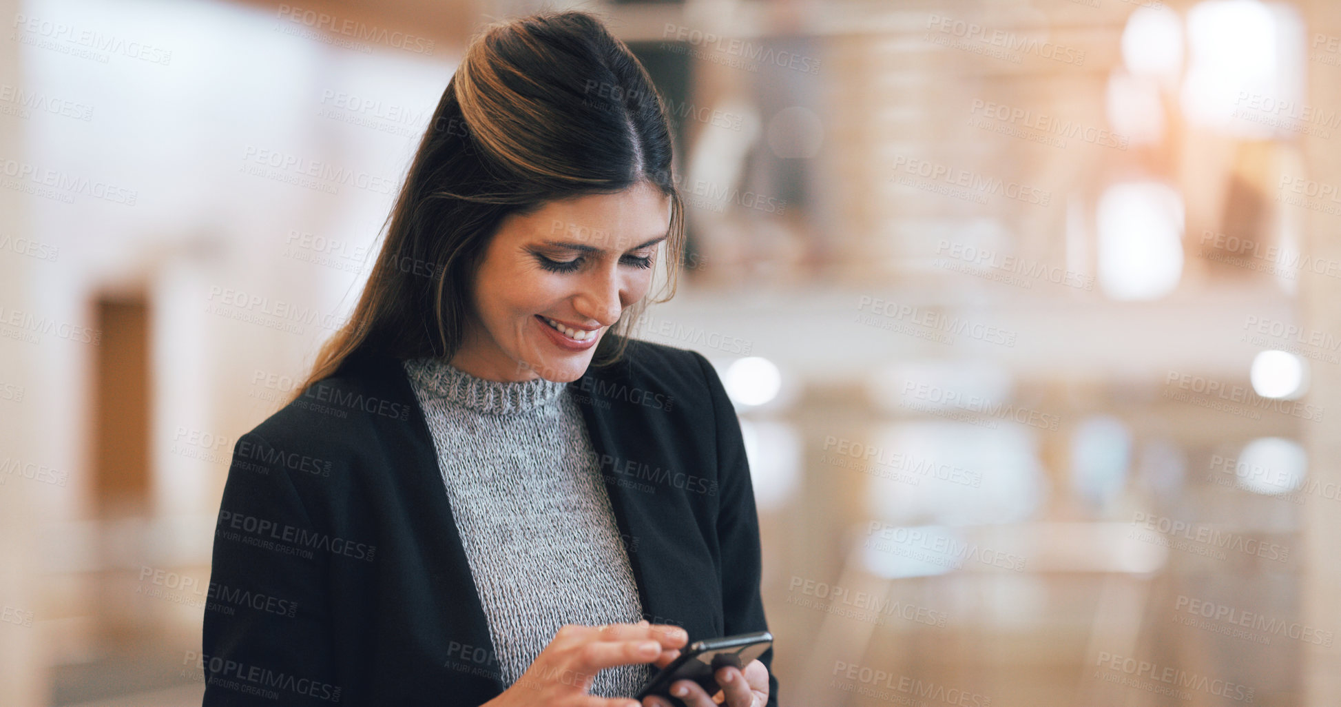 Buy stock photo Cropped shot of a an attractive young businesswoman smiling while using smartphone in a modern workplace