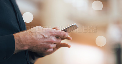 Buy stock photo Cropped shot of an unrecognizable businessman using a smartphone while standing in a modern workplace