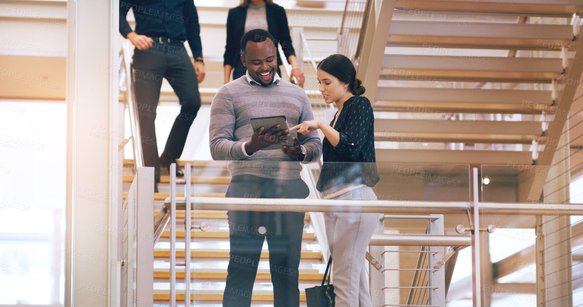 Buy stock photo Cropped shot of two young businesspeople using a digital tablet while standing in a modern workplace
