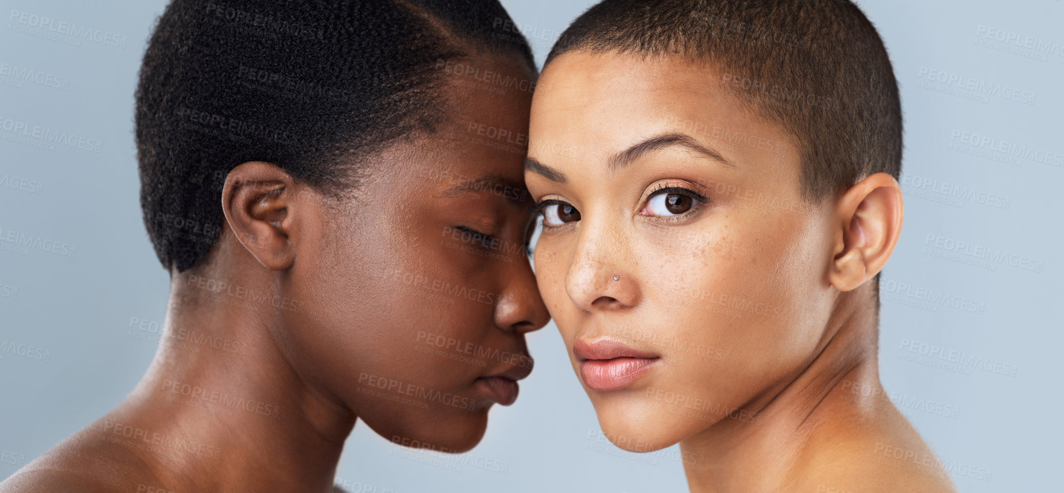 Buy stock photo Portrait of two beautiful young women standing close  to each other against a grey background