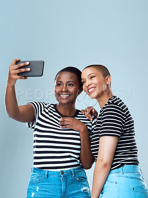 Buy stock photo Studio shot of two beautiful young women taking a selfie together against a grey background